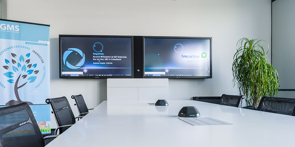 Showroom bei GMS mit Bildschirmen und Konferenztisch.