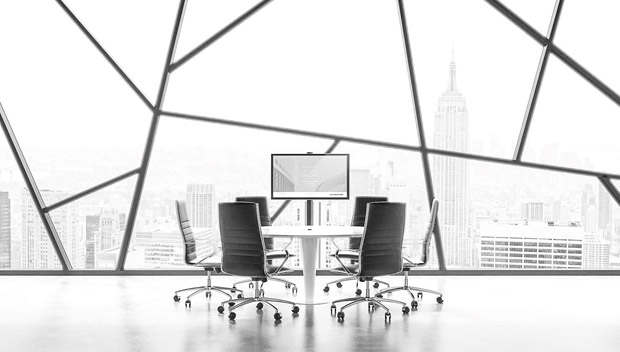 Runder Bürotisch mit Stühlen vor einer Fensterfront (Schwarzweiß).