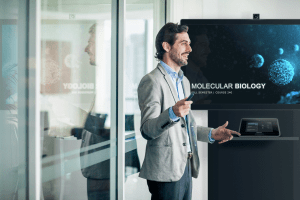 Mann präsentiert vor einem Microsoft Raumsystem von Creston