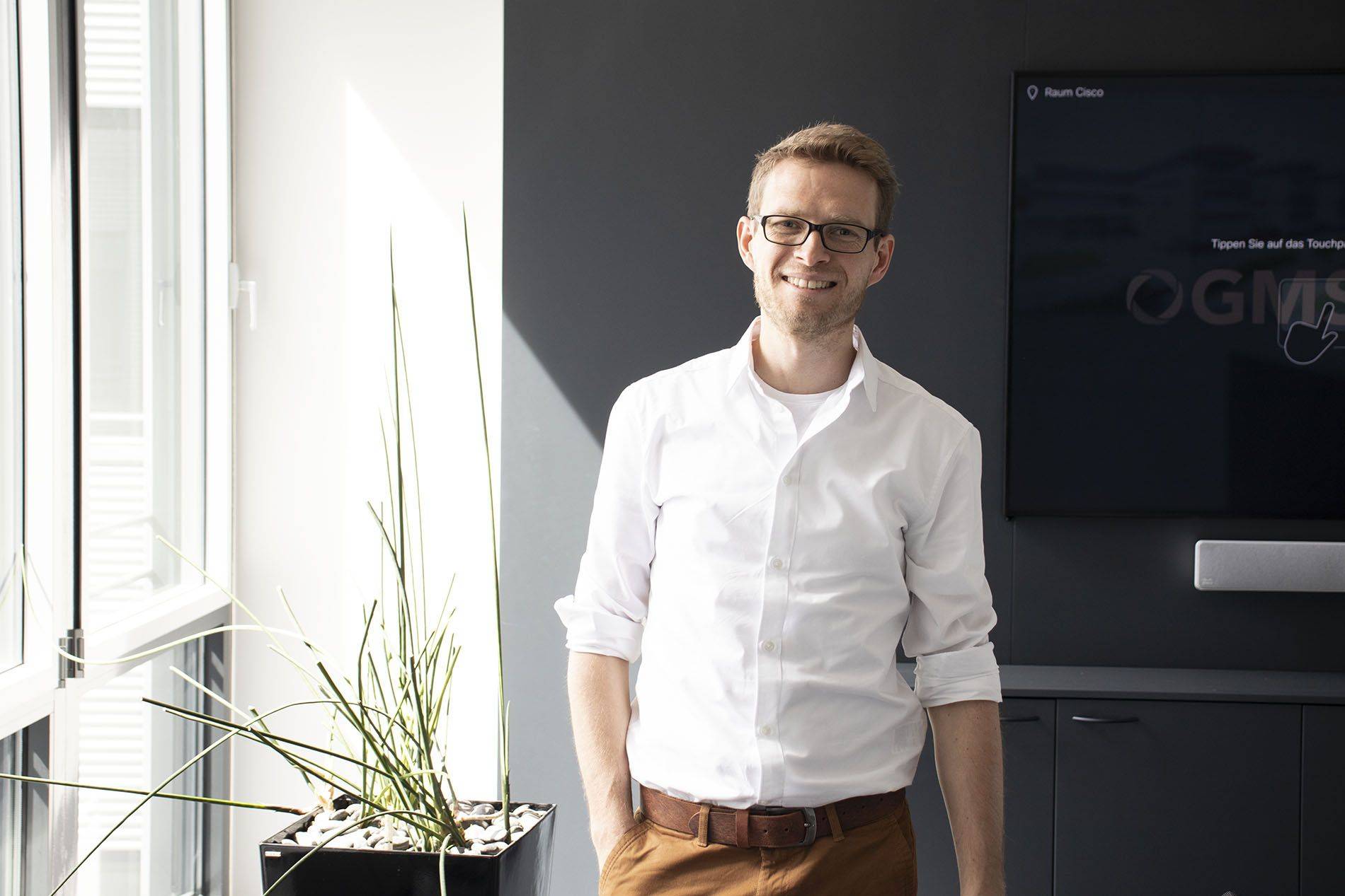 Ein Mann in einem weißen Hemd und braunen Hosen.