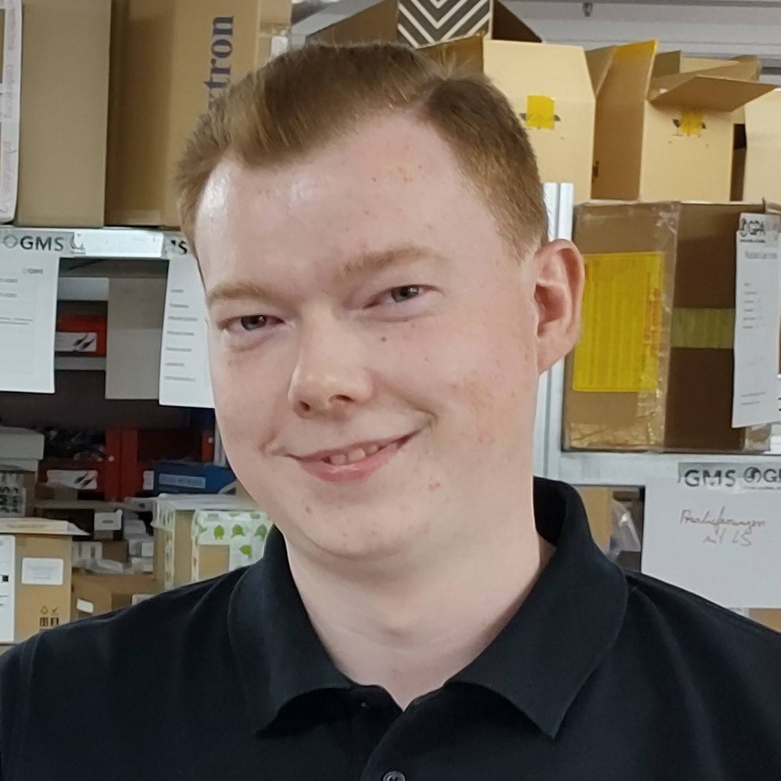 Ein Mann in einem schwarzen Hemd lächelt in die Kamera.